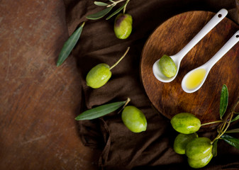 green olives, olive branch and olive oil on a dark wooden board