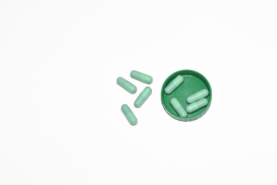 Group of green medical capsules on green lid,isolated on white with clipping path