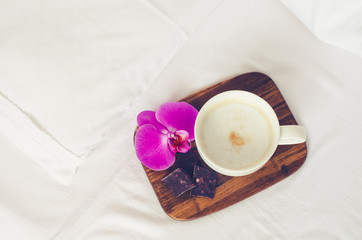 Cup of cappuccino on the bed