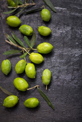 green olives and olive branch on a dark wooden board