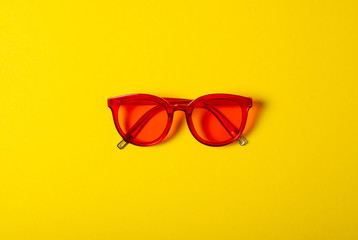 Red sunglasses fashion on yellow background, top view