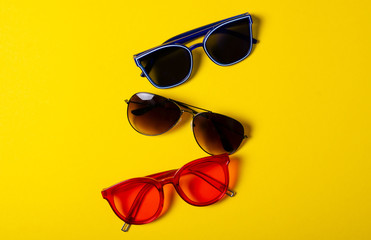 Sunglasses fashion style on yellow background, top view