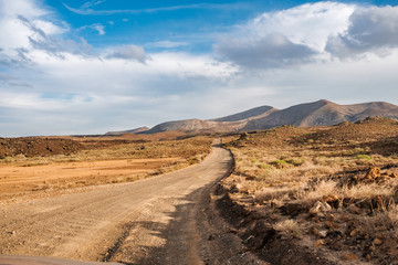 Empty dirtroad into the Lanzarote volcano based desert