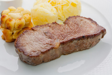 yorkshire pudding and roast beef with mashed potatoes and gravy on a white plate