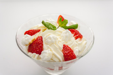 juicy strawberries with cream in a transparent glass bowl on a white background, top-side view