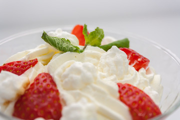 juicy strawberries with cream in a transparent glass bowl on a white background close-up