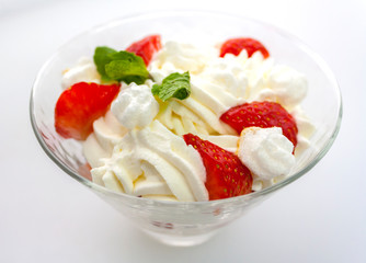 juicy strawberries with cream in a transparent glass bowl on a white background side view