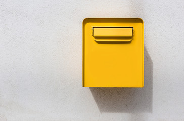 Yellow mailbox on white wall. Retro style