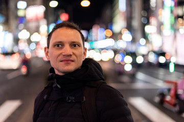 Tokyo, Japan Shinjuku district at night with young man portrait looking at nightlife with background of bokeh lights on street