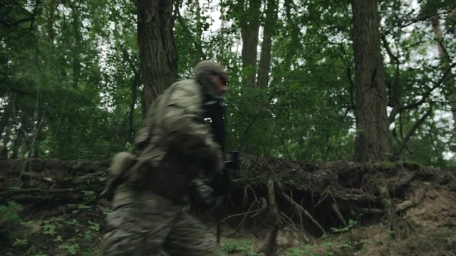 Military Operation in Action, Squad Running in Forest. Fully Equipped Soldiers Wearing Camouflage Uniform Attacking Enemy, Rifles Ready to Shoot. Slow Motion. Epic. 4K UHD