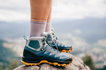 Mood photo of male legs wearing sportive hiking shoes with strong protective sole. Mens legs in...