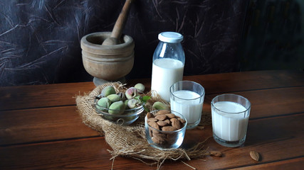 Almonds and fresh milk on wood background
