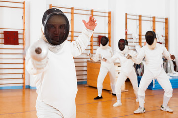 Sporty young man fencer practicing effective fencing techniques in training room