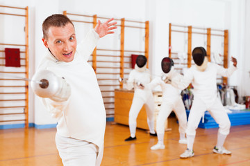 Sporty young man fencer practicing effective fencing techniques in training room