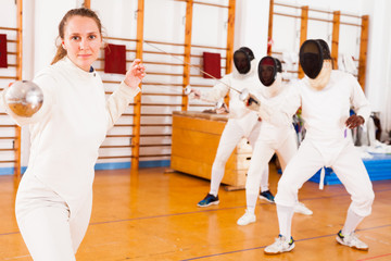 Young female fencer practicing fencing technique in training room
