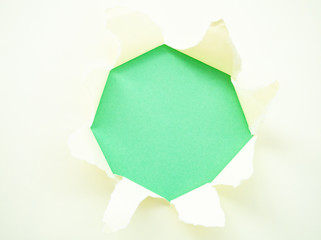 Torn pastel pastel yellow paper isolated on green