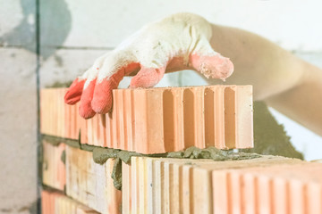 master with a tool, stacks a red brick. there is illumination and toning. shallow depth of cut.