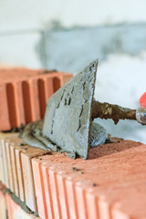 master with a tool, stacks a red brick. there is illumination and toning. shallow depth of cut.