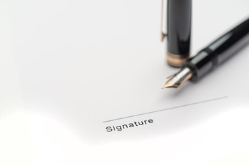 Black fountain pen on document pointing to signing area