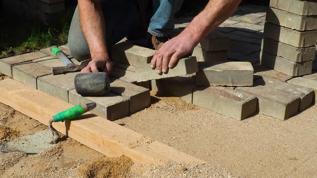 The builder is laying paving stones. worker puts sidewalk tile