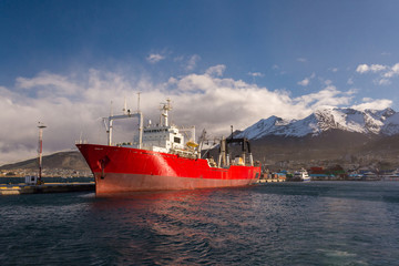 Red container ship in Ushuaia port. A big colorful cargo ship on beagle channel on a sunny winter...
