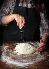 Chef hands cooking dough on dark wooden background.