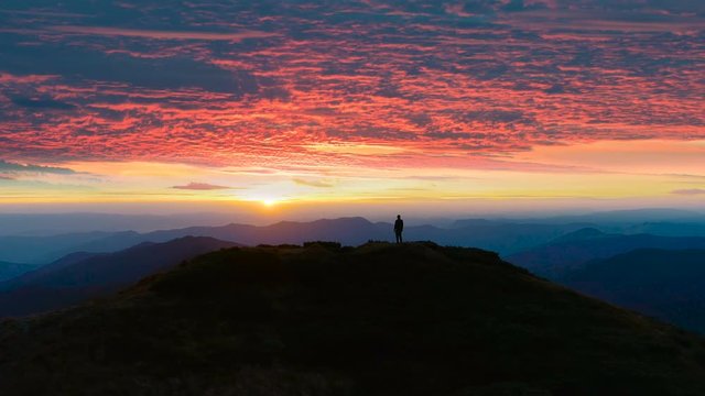 The man standing on the mountain on the sunset background