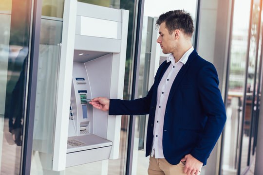 Young Business Man Using ATM. Person Using Credit Card To Withdrawing Money From Atm Machine.