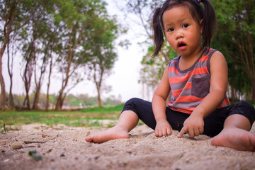 Naklejka na ściany i meble Happy child playing with sand, Funny Asian family in a park.