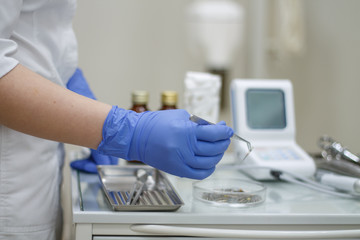 dental instruments in hand blue glove on background of dentistry tweezers and burs