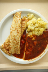 Crepes with potatoes and tomato ragout served on the tray for lunch