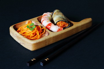 Exquisite original culinary dish of appetizing shrimp, pickled carrots and tubs of fried eggplant on beech tray on dark background. Concept — Asia, gourmet, restaurant, serving.