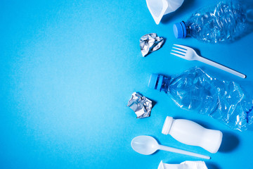 Plastic trash on blue background, eco concept image with copy space.