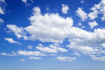 White fluffy clouds high in a bright blue sky on a sunny spring day. Crystal clear air, good weather.