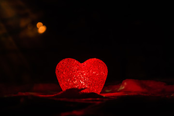 Glowing textured red heart in darkness symbolic of love and romance with copy space for a...