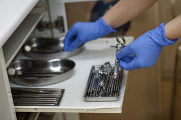hands in blue gloves holding dental tools from the locker Bura syringe