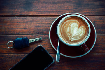Cup of hot coffee,books,smart phone and keys on the wood plate