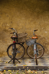 Fototapeta na wymiar Una pareja de bicicletas frente a un muro ocre en otoño