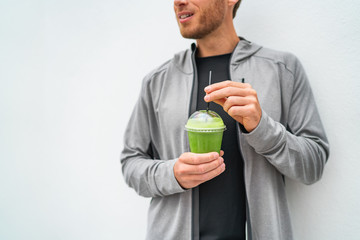 Healthy young man drinking green juice smoothie cup as weight loss detox meal replacement diet....