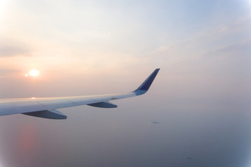 airplane wings during sunset in a clear pinky sky.