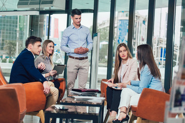 Business team working on new project and smiling. Man and women sitting together in modern office for project discussion.