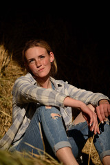 young beautiful girl with freckles in denim overalls in the hayloft