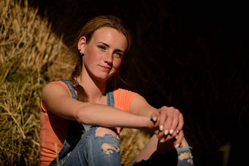 young beautiful girl with freckles in denim overalls in the hayloft