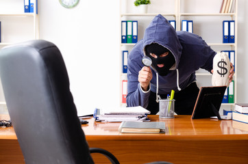 Male thief in balaclava in the office 