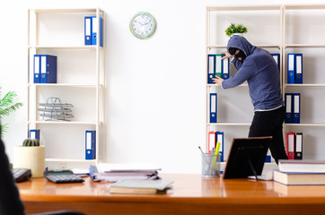 Male thief in balaclava in the office 