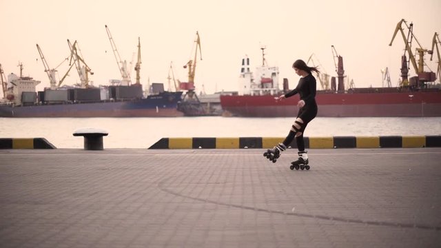 Woman skating by the sea. The girl goes rollerblading and does tricks and stretching on the rollers. Caucasian woman outdoor at sunrise