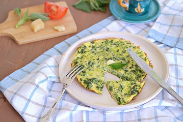 Breakfast, omelet with nettles on a white clay plate. Healthy food. Food from wild herbs.