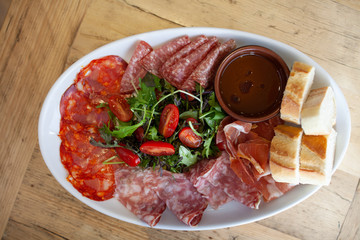 A platter of mixed cured meats and salad served with sliced french bread