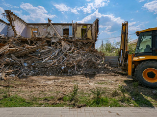 Destruction of walls of old building and cleaning of construction debris with bucket of...