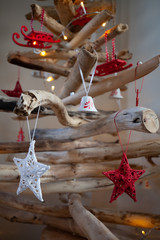 A wooden Christmas tree with white fairy lights and red & white decorations hanging from it